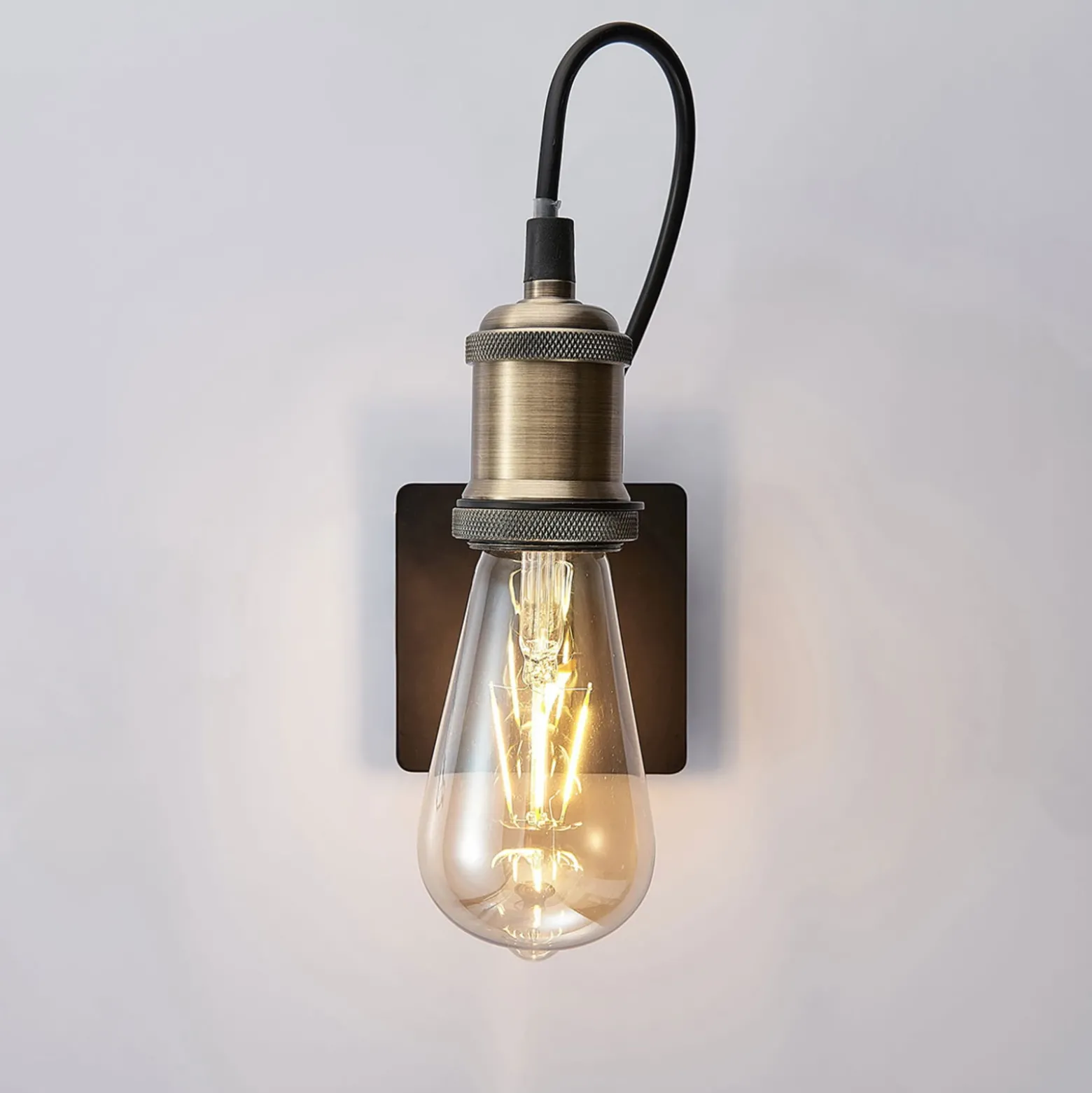 Aplique de pared Lindby Aurella, altura 16 cm, latón envejecido, metal