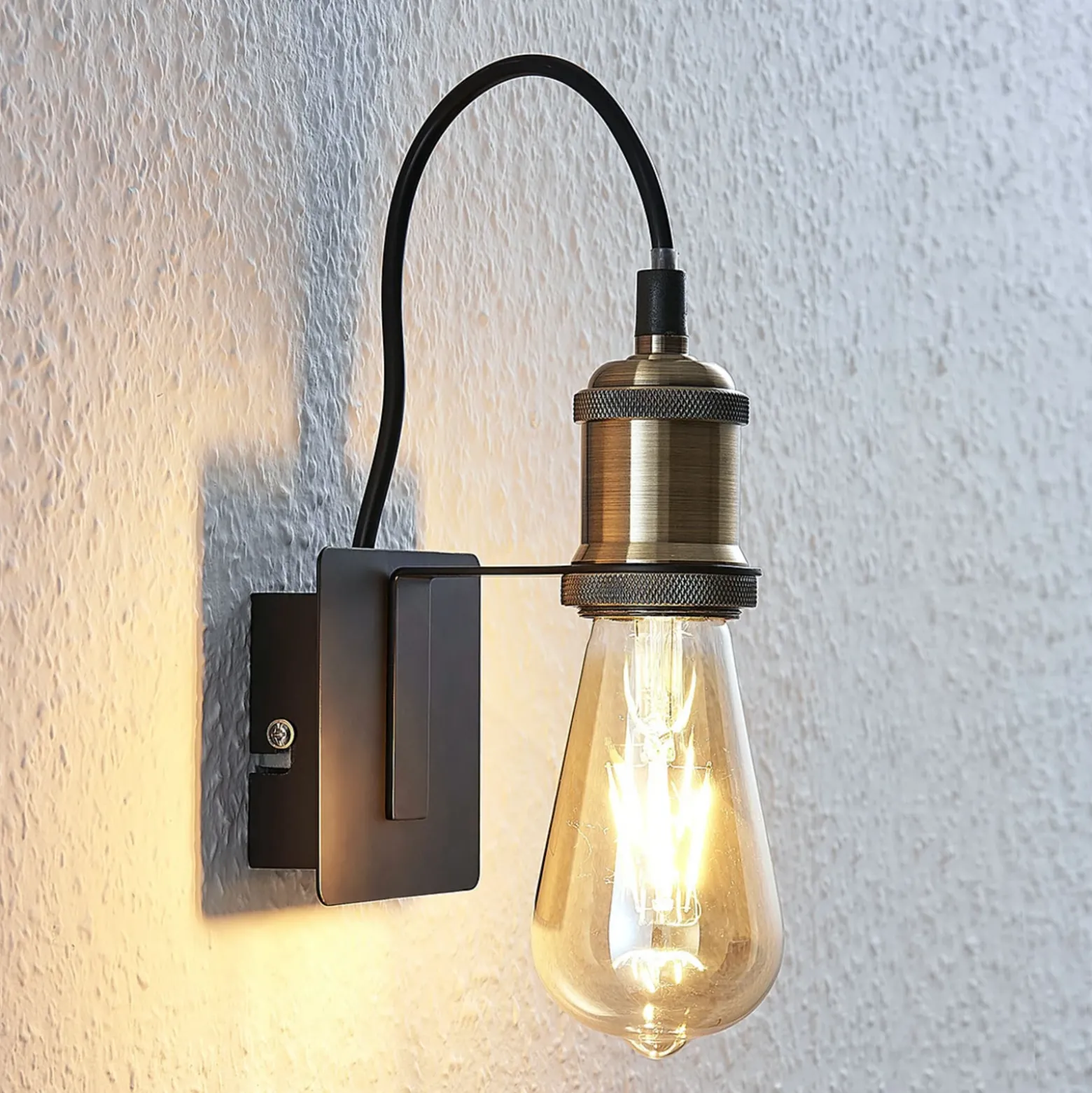 Aplique de pared Lindby Aurella, altura 16 cm, latón envejecido, metal