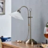 Lámpara de mesa Otis de Lindby, latón antiguo, cristal, 60 cm, E14